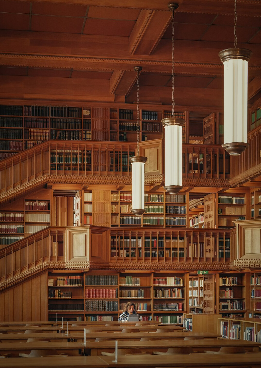 Interior of an old library with tall wooden bookshelves and warm light