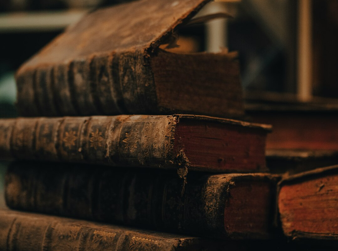 Stack of old leather-bound books with a magnifying glass on top