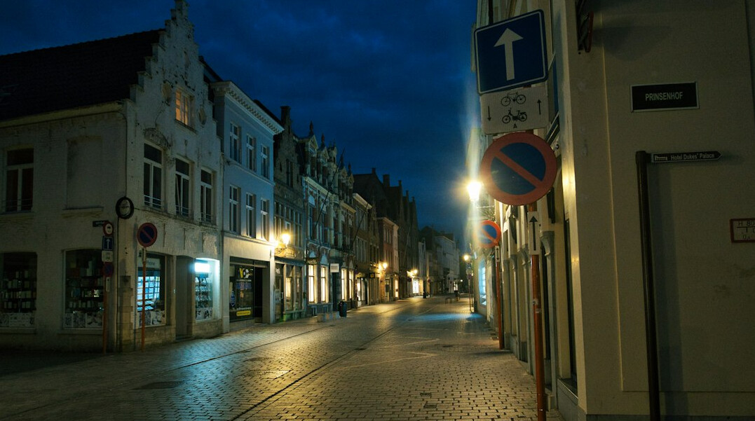 Foggy cobblestone street at night with a single glowing streetlamp