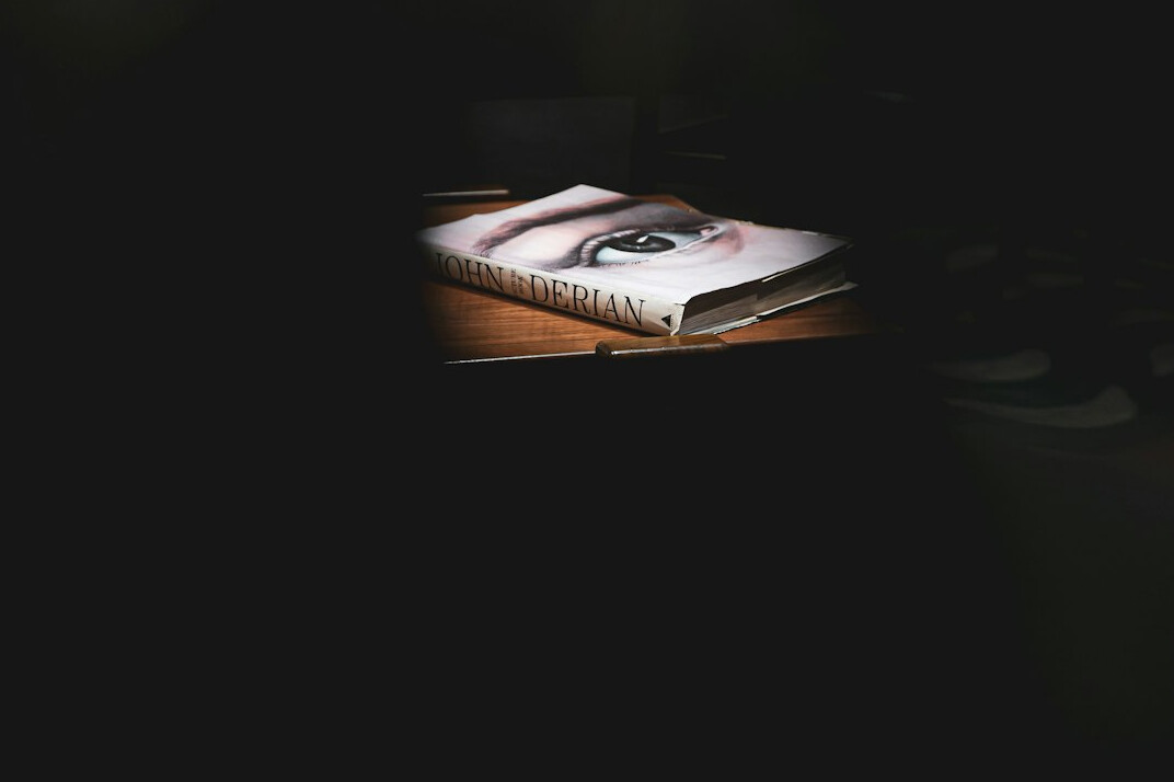 Open detective notebook with a magnifying glass and old photographs on a wooden desk